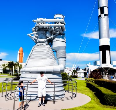 Kai and Kenny relax in front of the F-1 engine. The F-1 is the engine that sent the Saturn V on its way toward the moon. If you had something that weighed a million pounds, this engine, all by itself, could lift it off of the ground and into the sky with ease. Imagine that. It has been a long day, marveling once again at the wonders arrayed all around them at the Kennedy Space Center. It is time now to go back home. Kai and Kenny enjoyed their trip very much, and they hope you enjoyed seeing these pictures, and they thank you for coming along to share this little bit of their experience with them